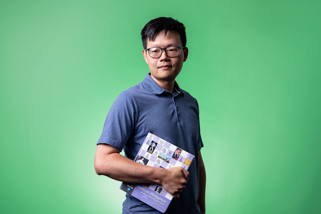 a man with glasses holds a textbook