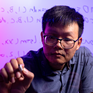 a man performs calculations on a clear dry erase board