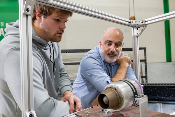 a professor and student examine an aerospace engine in a test stand