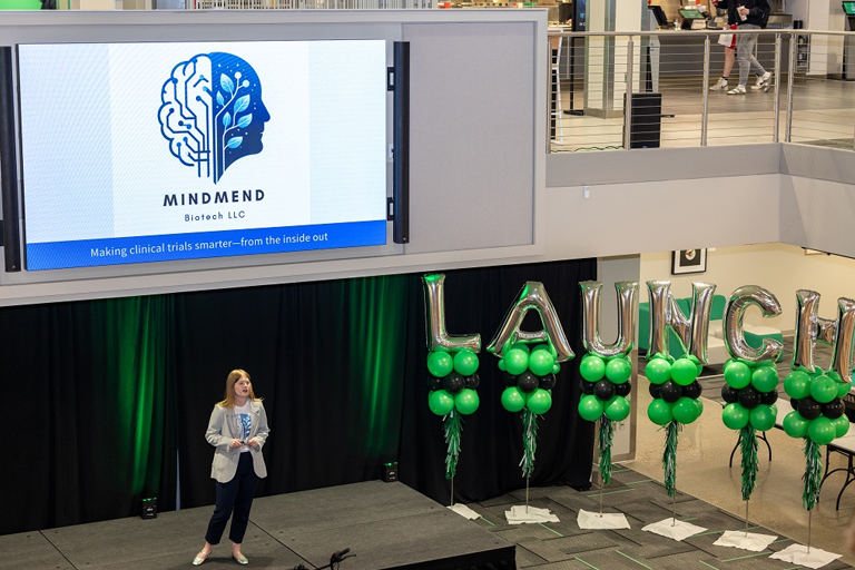 a woman stands on stage giving a presentation