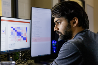 s student looks at multiple monitors in a cyber security lab