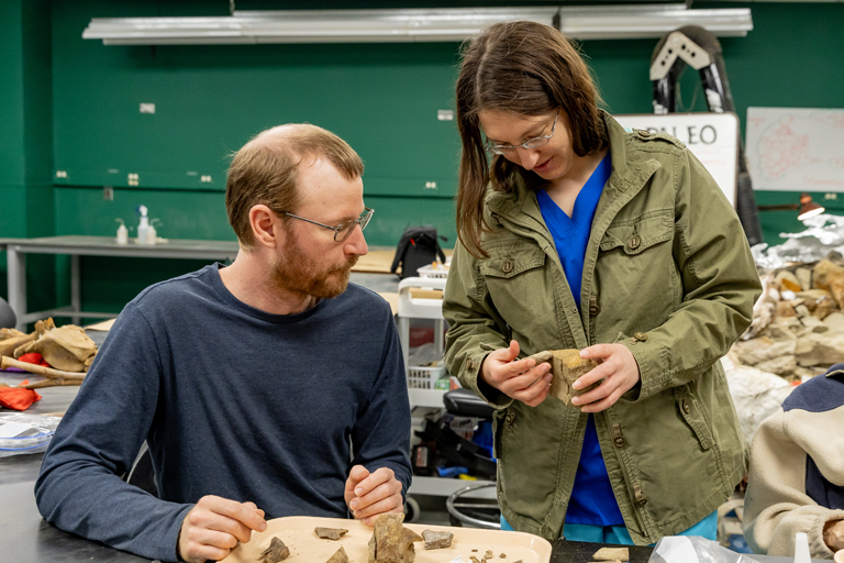 two scientists, a man and a woman examine a fossil in a lab