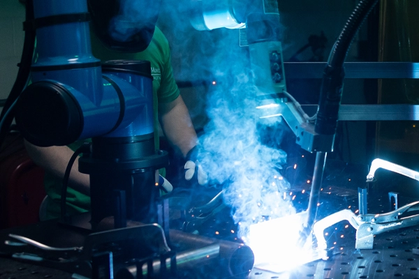 a person in a green shirt works with a large welding maching