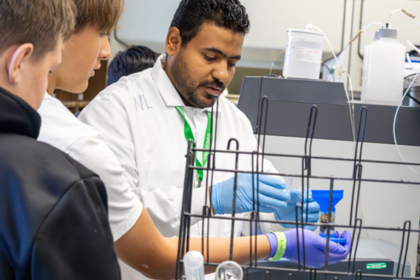 students watch a faculty member conduct an experiment