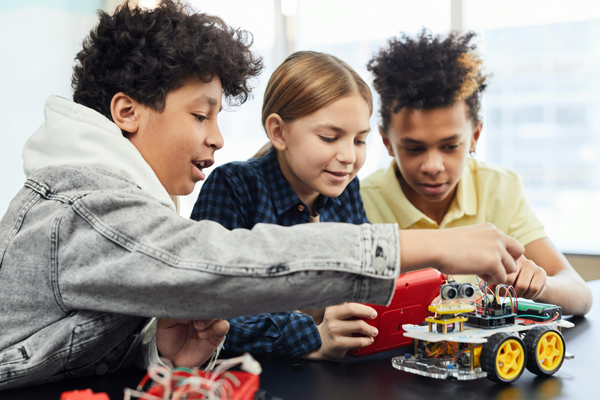 three grade school students study a robot