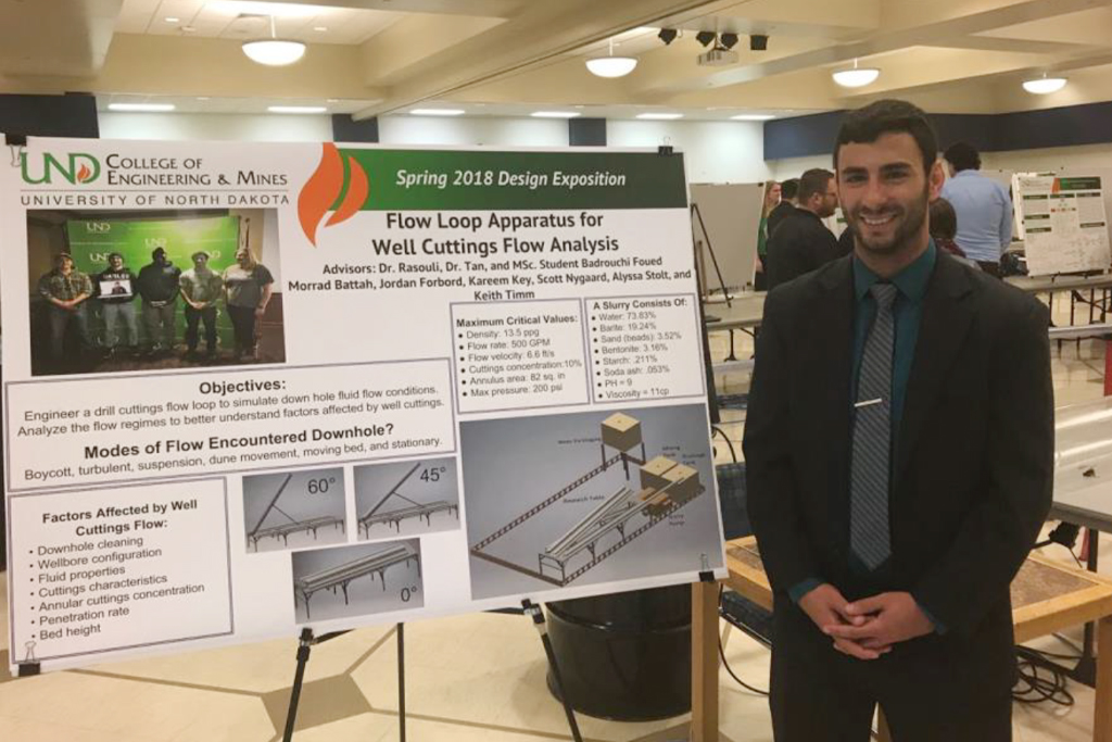 a male student poses with a poster at the 2018 senior design expo