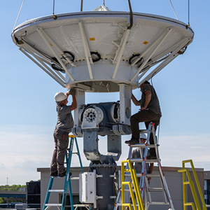 two men work on a large antenna