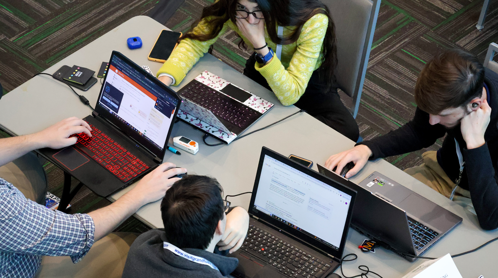 college students at a table work on laptops